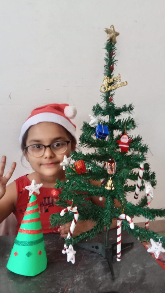 She is decorating a christmas tree for a cyboard school christmas celebration